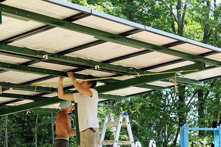 PV installers working underneath a pole mounted array.